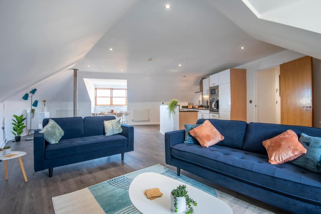 een woonkamer met twee blauwe banken en een keuken bij The Balham Loft - NEW Gorgeously appointed with FREE parking and tube close by in Londen