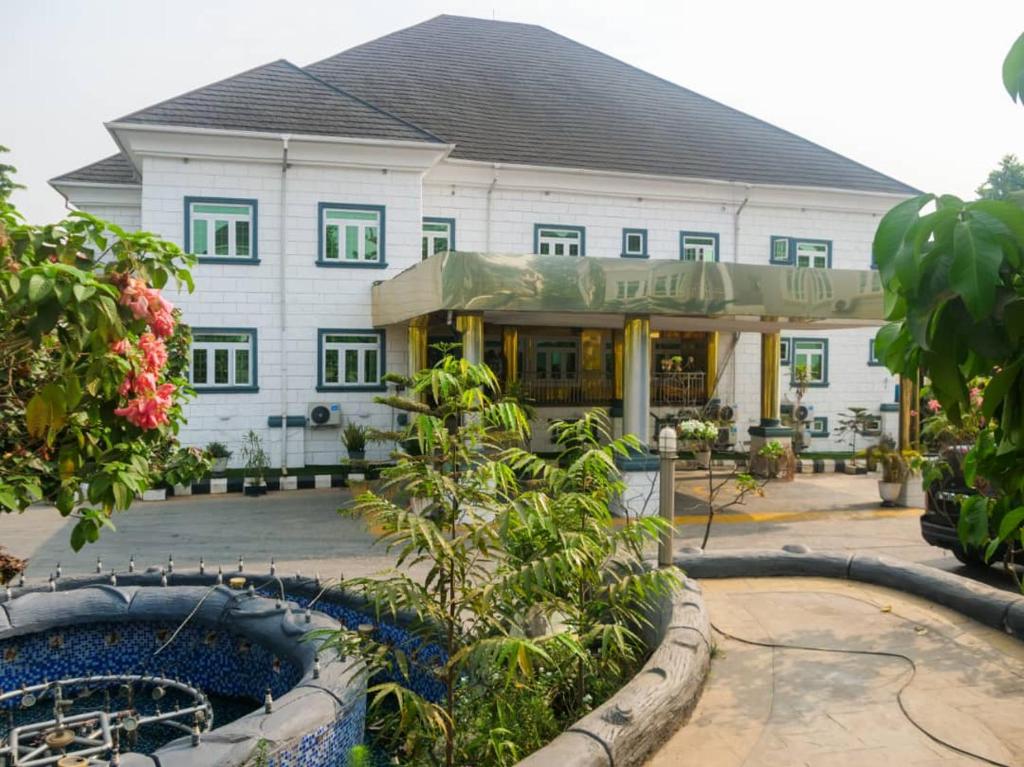 a large white building with green windows at Hotel Belisco in Owerri