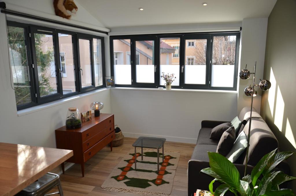 sala de estar con ventanas grandes y sofá en La Griotte - Studio tout confort - Lyon - Tassin, en Tassin-la-Demi-Lune