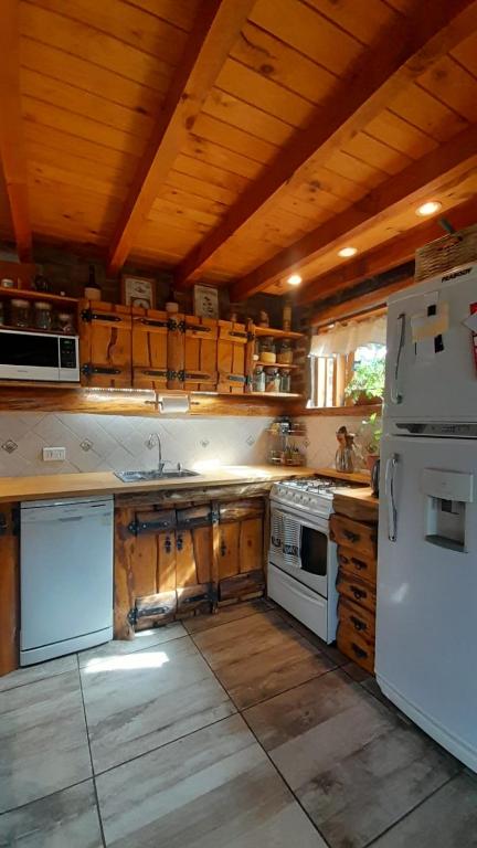 Il comprend une cuisine avec des appareils blancs et un plafond en bois. dans l'établissement Hermosa casa familiar, à San Carlos de Bariloche