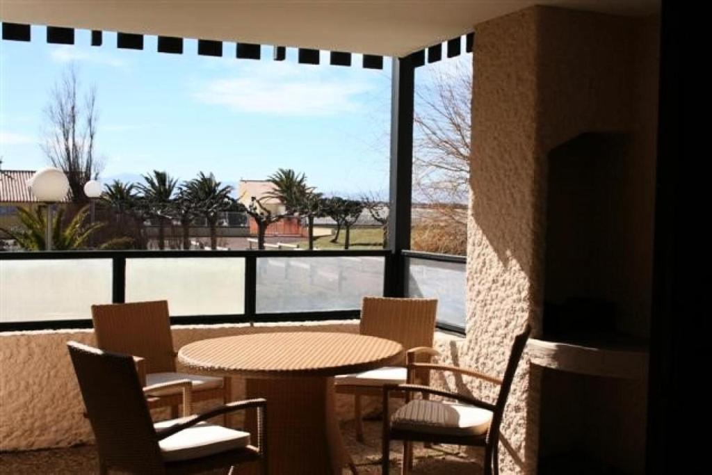 een patio met een tafel en stoelen en een groot raam bij Résidence Bd Guadeloupe - 3 Pièces pour 6 Personnes 464 in Le Barcarès