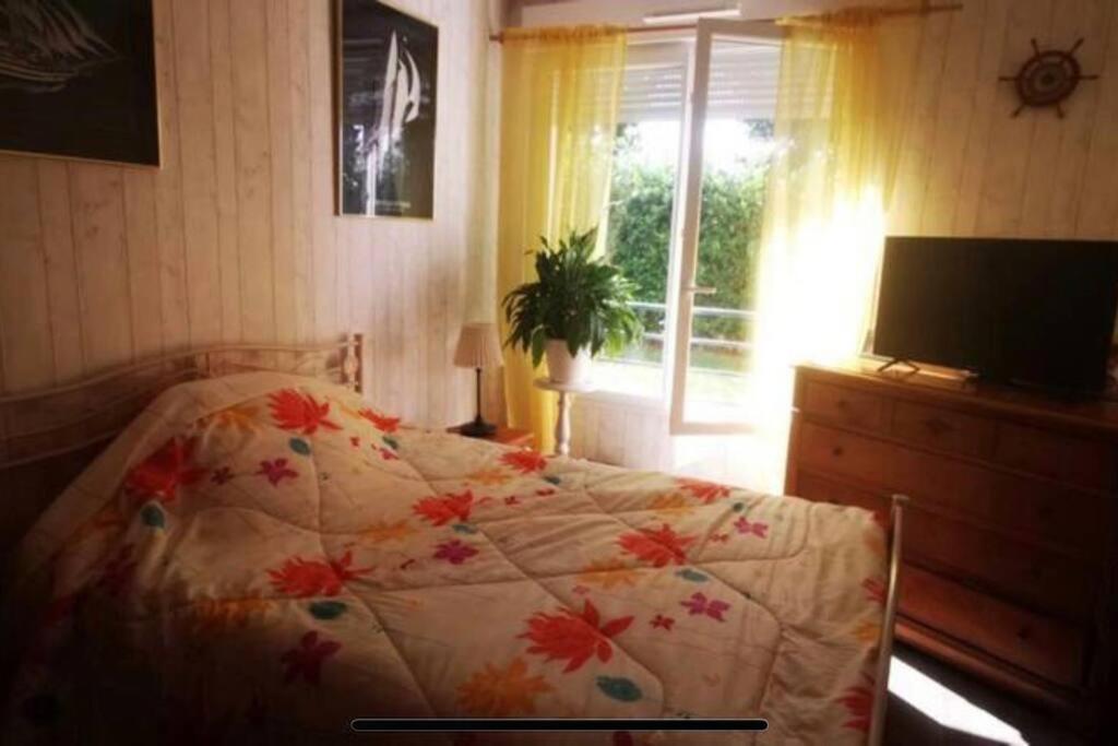 a bedroom with a bed with a flowered blanket and a window at Lovely room,Rambouillet in Rambouillet
