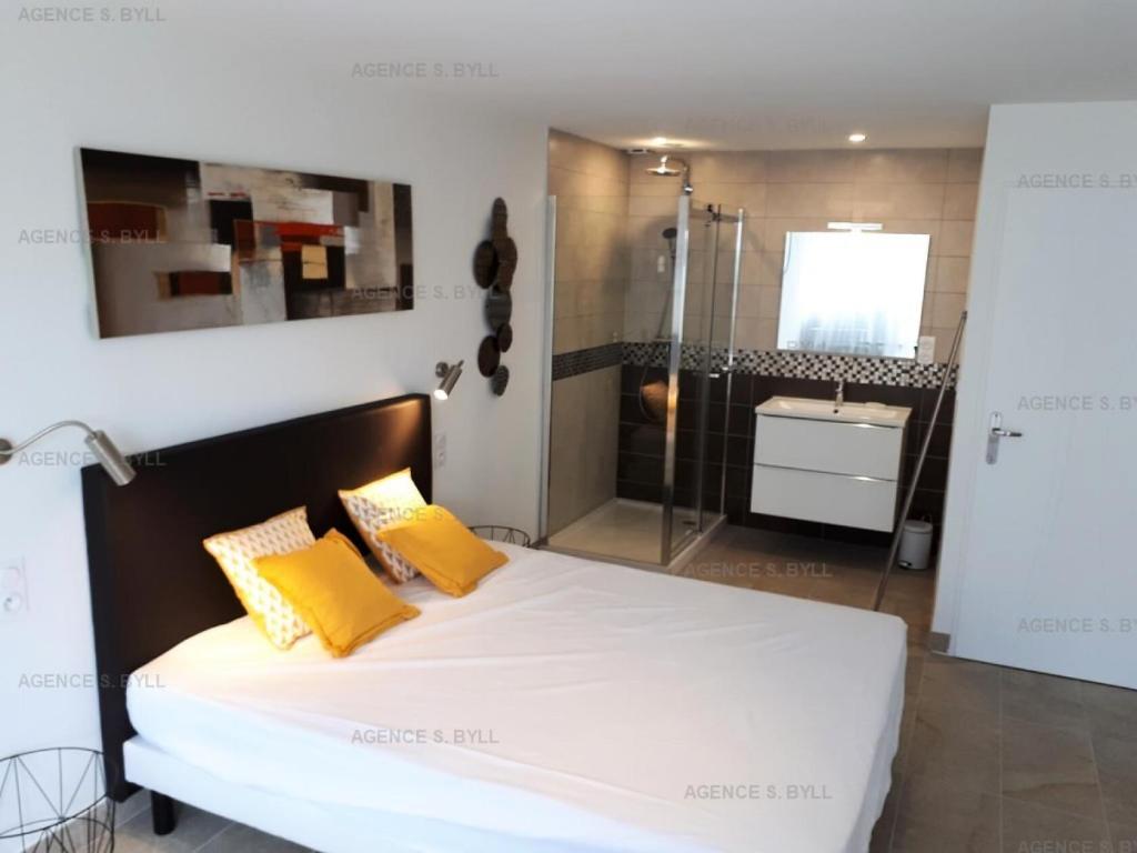ein Schlafzimmer mit einem Bett mit gelben Kissen und einer Dusche in der Unterkunft Résidence Héliopolis Bâtiment D - Appartements pour 2 Personnes 584 - Naturiste in Cap d'Agde