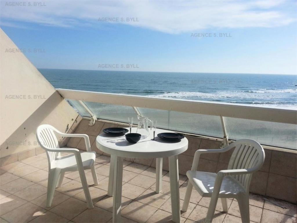 une table blanche et des chaises sur un balcon avec l'océan dans l'établissement Résidence Héliopolis Bâtiment C - Héliopolis Bât. C studio 2 Pers. MAE-5474, au Cap d'Agde