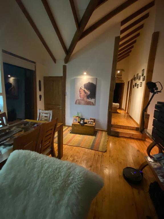 una sala de estar con suelo de madera y una pintura en la pared en Habitación en Casa Cumbres del Lago en Puerto Varas
