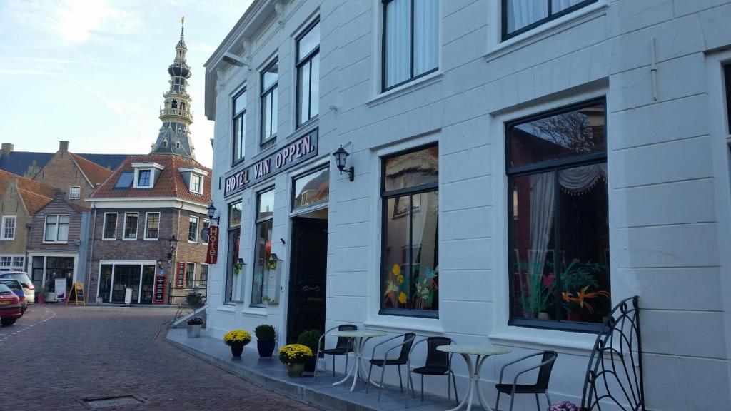 ein weißes Gebäude mit Tischen und Stühlen auf einer Straße in der Unterkunft Hotel van Oppen in Zierikzee