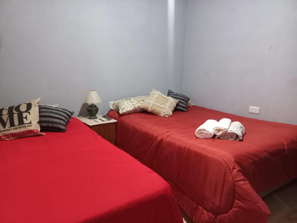 two beds in a room with red sheets at Vista a la montaña in Chilecito