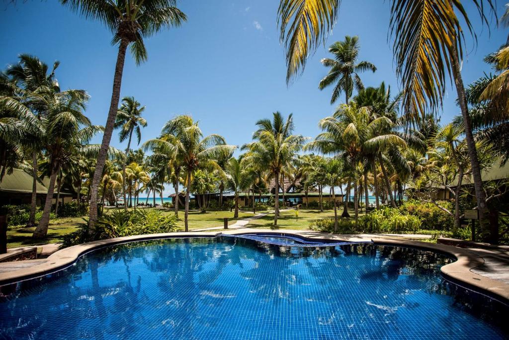 uma grande piscina com palmeiras ao fundo em Paradise Sun Hotel Seychelles em Baie Sainte Anne