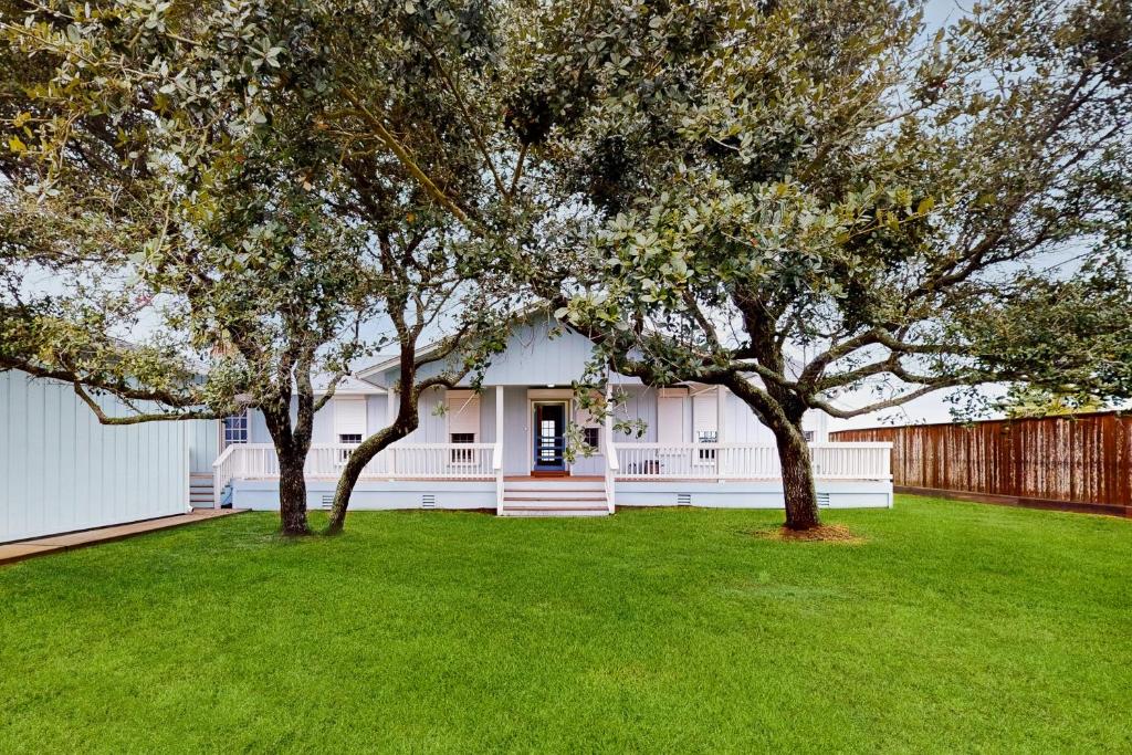 une maison blanche avec deux arbres dans une cour dans l'établissement Getaway on the Bay, à Rockport