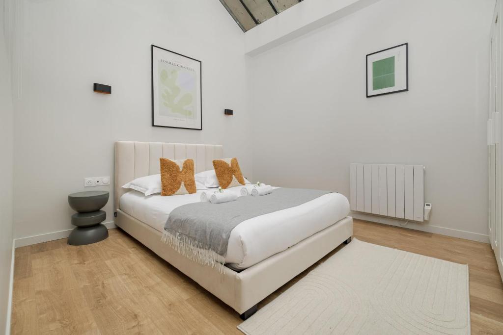 une chambre blanche avec un lit blanc avec des oreillers marron dans l'établissement Poetic Stay - Montmartre, à Paris