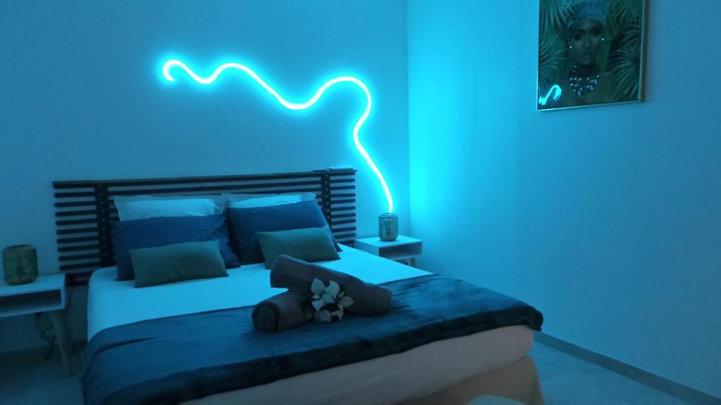 1 dormitorio azul con 1 cama con luz azul en T3 Proche des plages - Calme - Parking privé, en Le Diamant