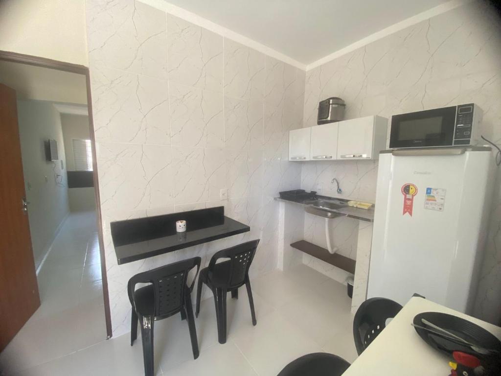 una pequeña cocina con sillas negras y nevera. en Residencial pimenta - aluguel temporada - apto mobiliado en Cuiabá