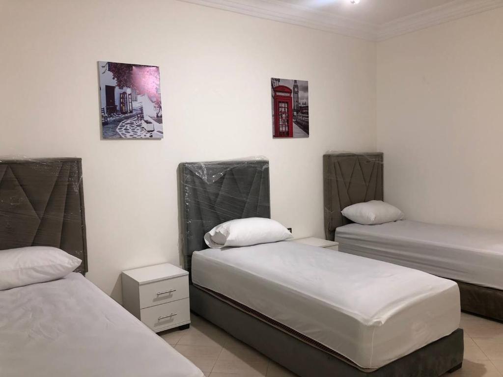 Cette chambre comprend 2 lits et 2 photos sur le mur. dans l'établissement Fantastique Appartement Nouveau meublé avec WIFI & NETFLIX à proximité du MARJANE M2, à Tanger