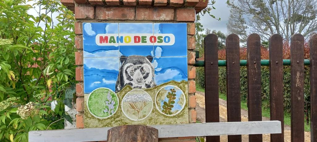 Ein Schild mit einem Hund vor einem Zaun. in der Unterkunft Mano de Oso Guasca in Guasca