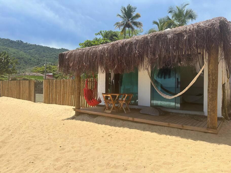 una pequeña casa con una hamaca en la playa en Casa beiramar Provetá IlhaGrande en Angra dos Reis