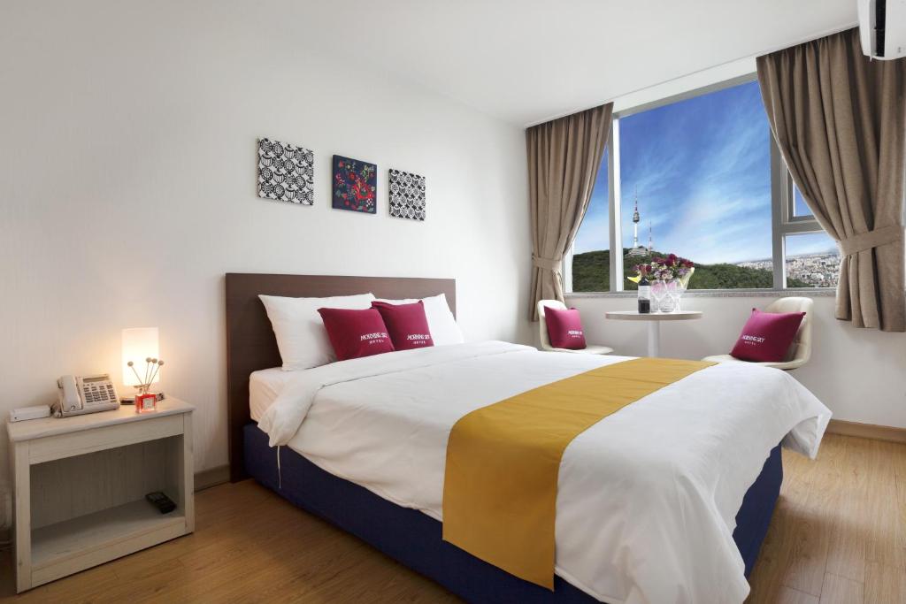 ein Schlafzimmer mit einem großen Bett und einem großen Fenster in der Unterkunft Hotel Morning Sky in Seoul