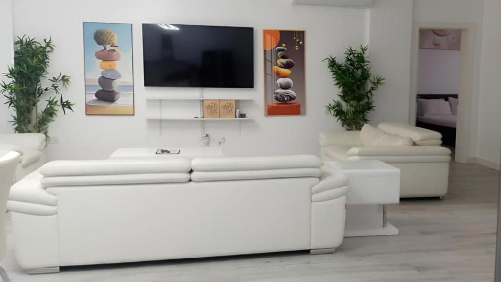 a living room with white furniture and a flat screen tv at White-House in Kigali