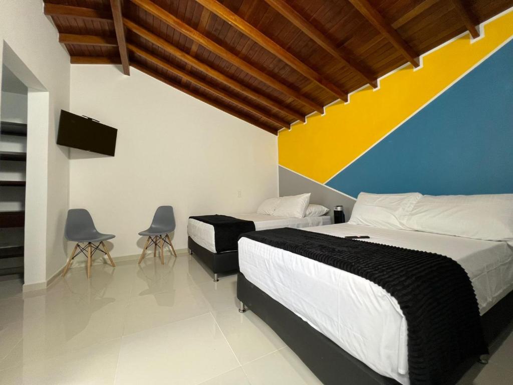a bedroom with two beds and two chairs at HOSPEDAJE TRIANON in Envigado