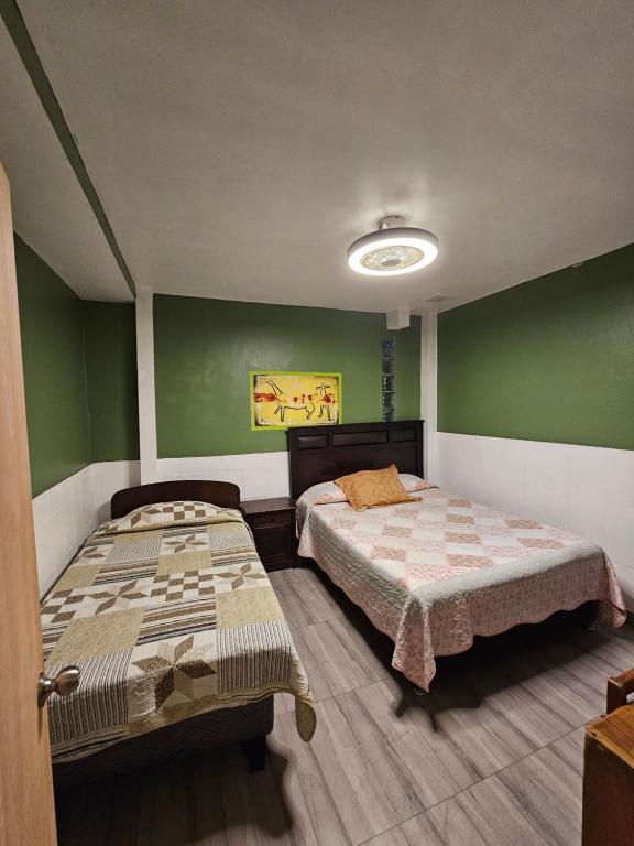 two beds in a room with green walls at Hostal Copa Arica in Arica