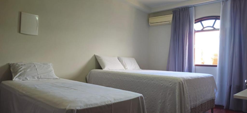 2 camas en una habitación con ventana en CAXU HOSTEL, en Cachoeiro de Itapemirim