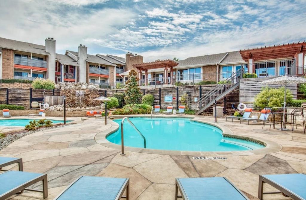 a pool with tables and chairs in front of a building at elegant stylish living in Arlington