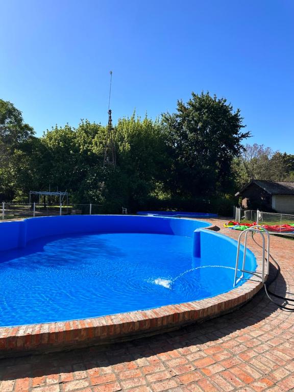 uma grande piscina azul com um pátio de tijolos vermelhos em La carmencita Club de Campo em Ingeniero J. Allan