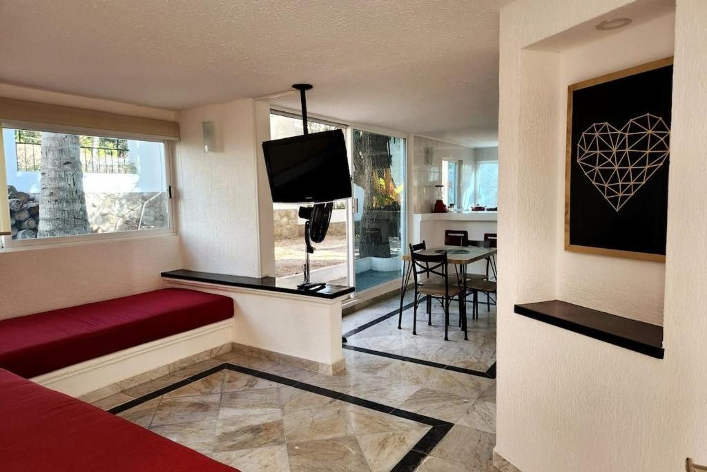 a living room with a red couch and a tv at Secretos del Sol Acapulco villas a 5 minutosdel mar in Acapulco