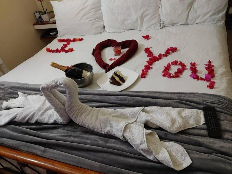 Una cama con un corazón hecho de adornos rojos en Orchid Inn en Montego Bay