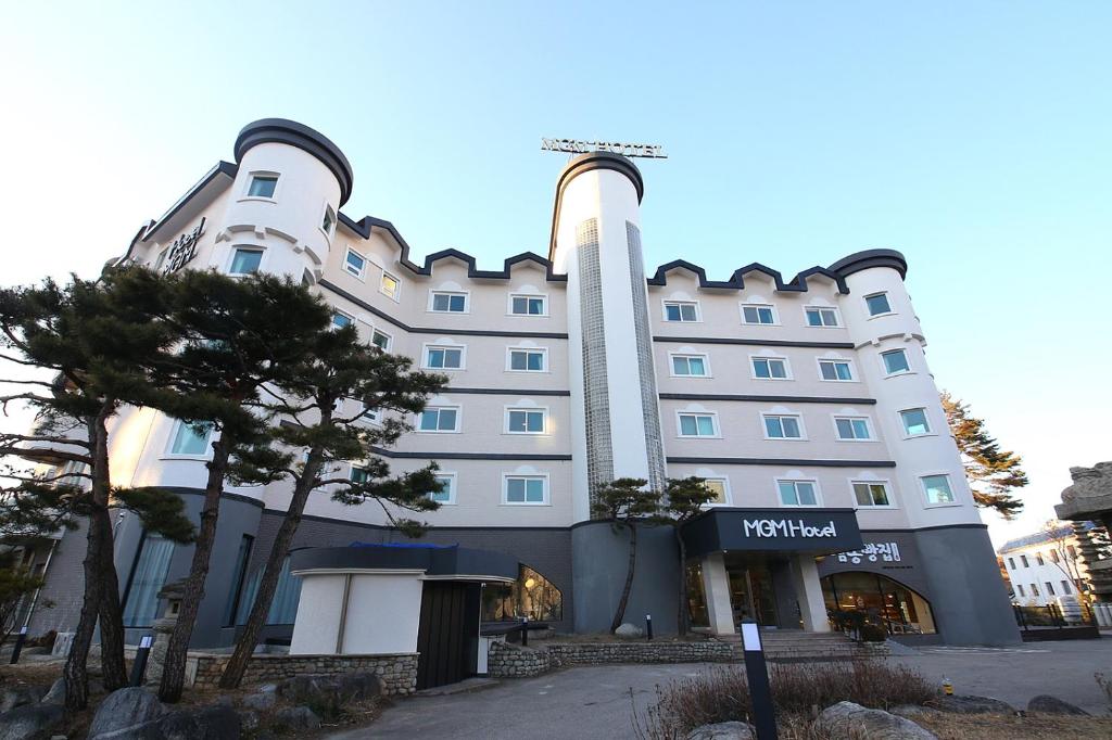 a large white building with a tree in front of it at MGM Hotel in Gangneung