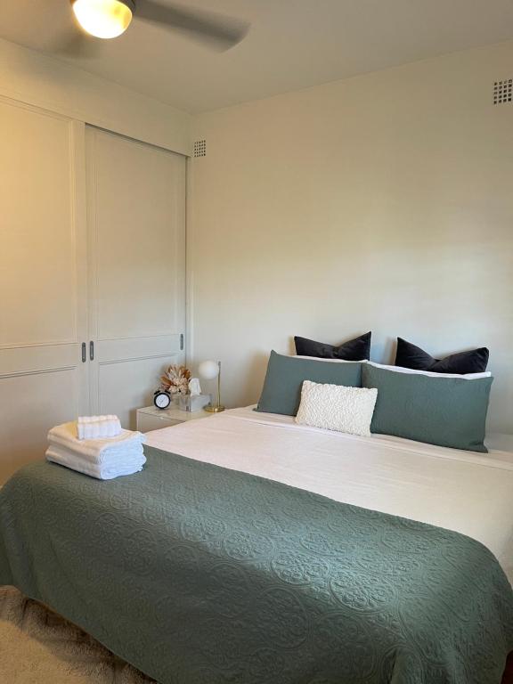 um quarto com uma cama grande e almofadas azuis em Charming & Cozy 2BR Cottage em Blacktown
