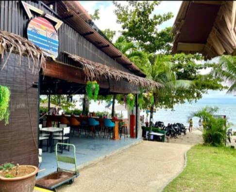 a building with a patio with tables and chairs at beachfront sea in Tanjung Bungah