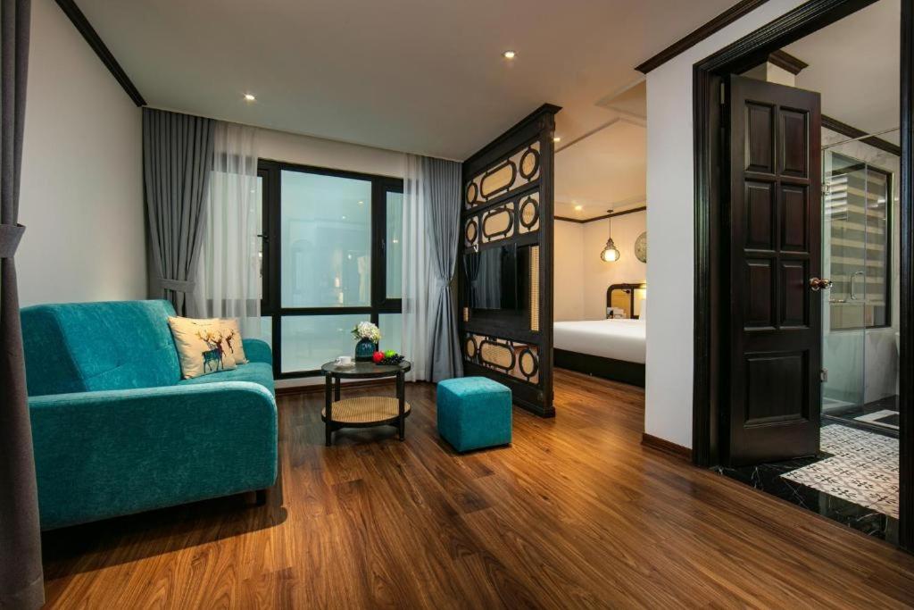 a living room with a blue couch and a bedroom at Media Central Hanoi Hotel - 108 Hàng Bạc - by Bay Luxury in Hanoi