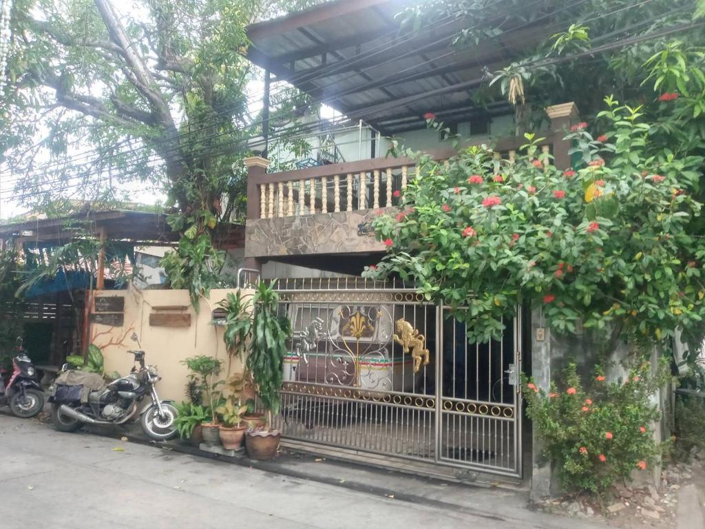 a house with a gate and some plants and a motorcycle at Best Place Have Air Conditioner in Bangkok