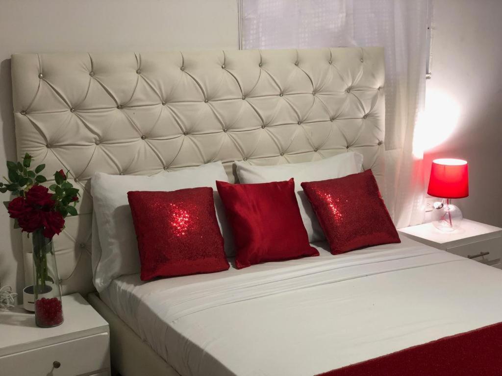 a white bed with two red pillows and a red lamp at hostal la casa de mi abuela in Barranquilla