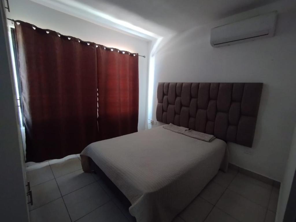 una camera con un grande letto con testiera marrone di Departamento Azul Marino Cerritos a Mazatlán