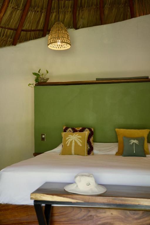 a bedroom with a large bed with a green wall at Casa MexiBali, Palapa Queen in La Majahua