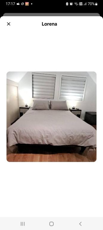a bedroom with a white bed with two windows at Lorena in Concepción