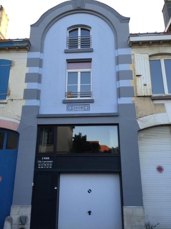 a blue building with two garage doors and a window at Gîte 1908 avec GARAGE in Wimereux