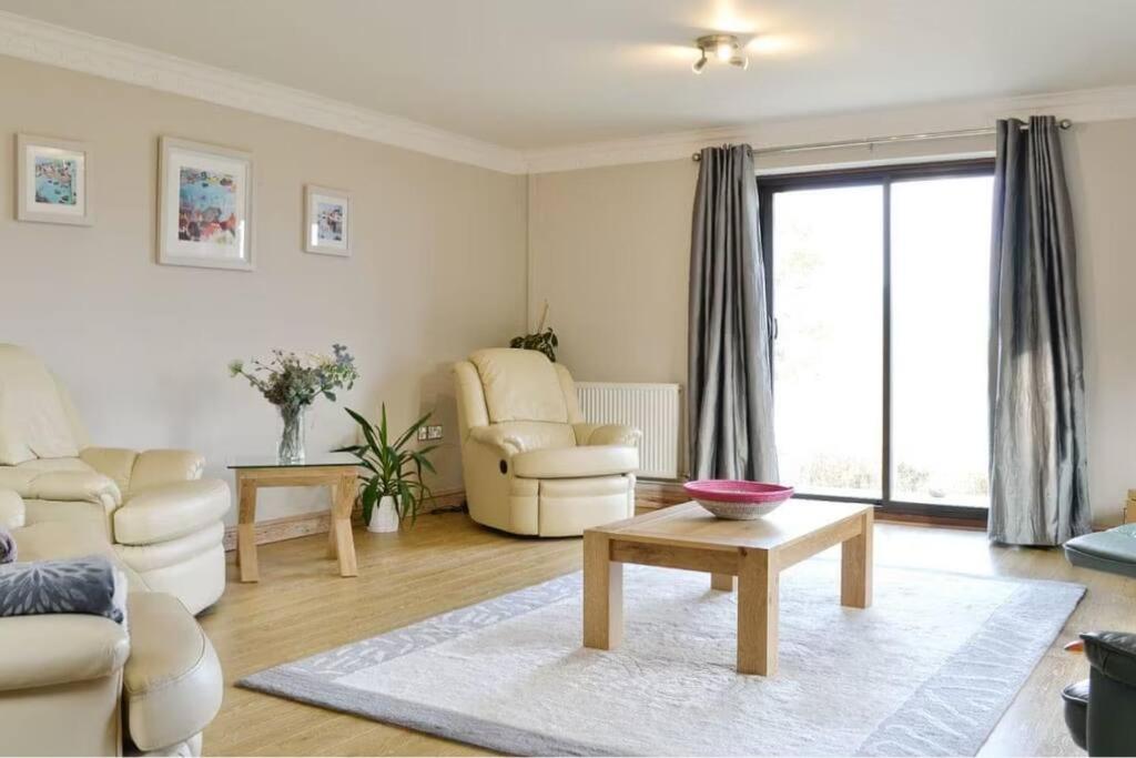 a living room with a couch and chairs and a table at Spacious bungalow with estuary views in Carmarthen