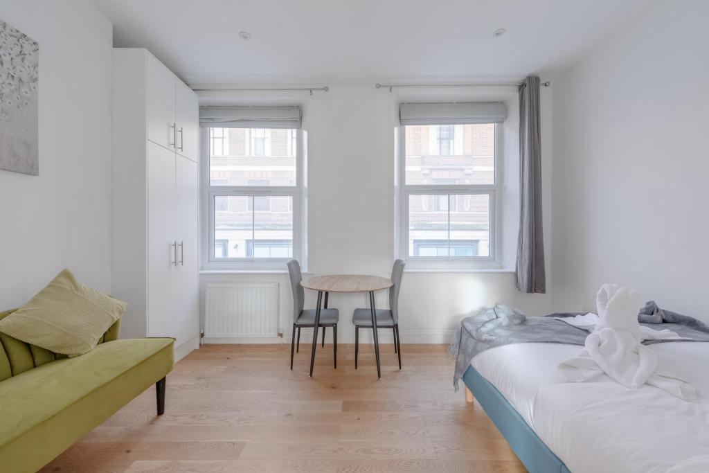 a bedroom with two beds and a table and chairs at HAFH in Paddington - Double studio 1 in London
