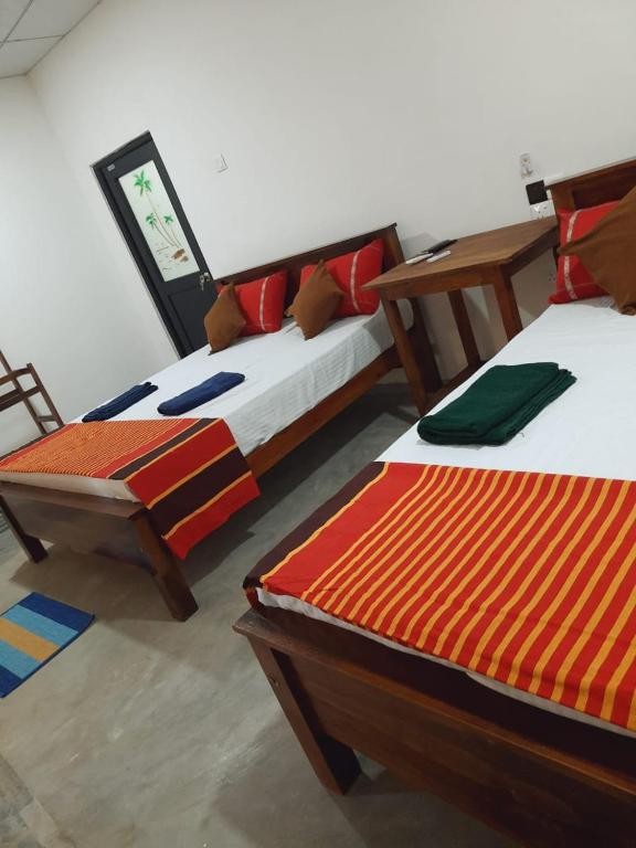 duas camas sentadas uma ao lado da outra num quarto em JD Resort em Anuradhapura