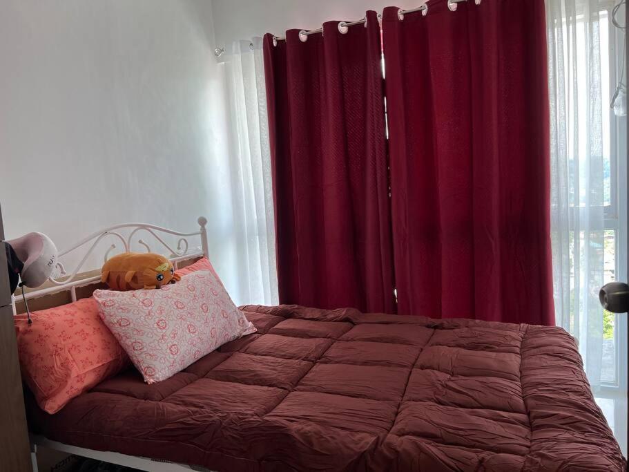 a bedroom with a bed with red curtains at Uptown Condo Primavera Residences in Cagayan de Oro