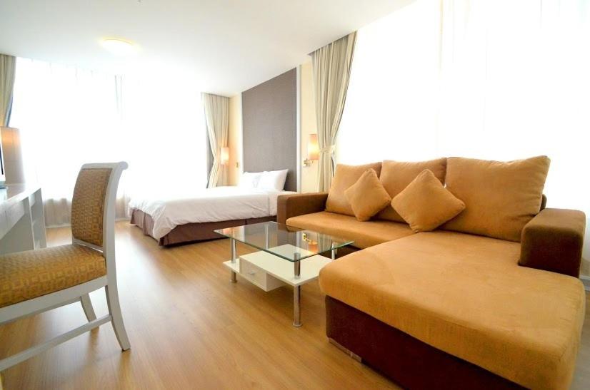 un soggiorno con divano e letto di The City Hotel Sriracha by BBH Japan a Si Racha