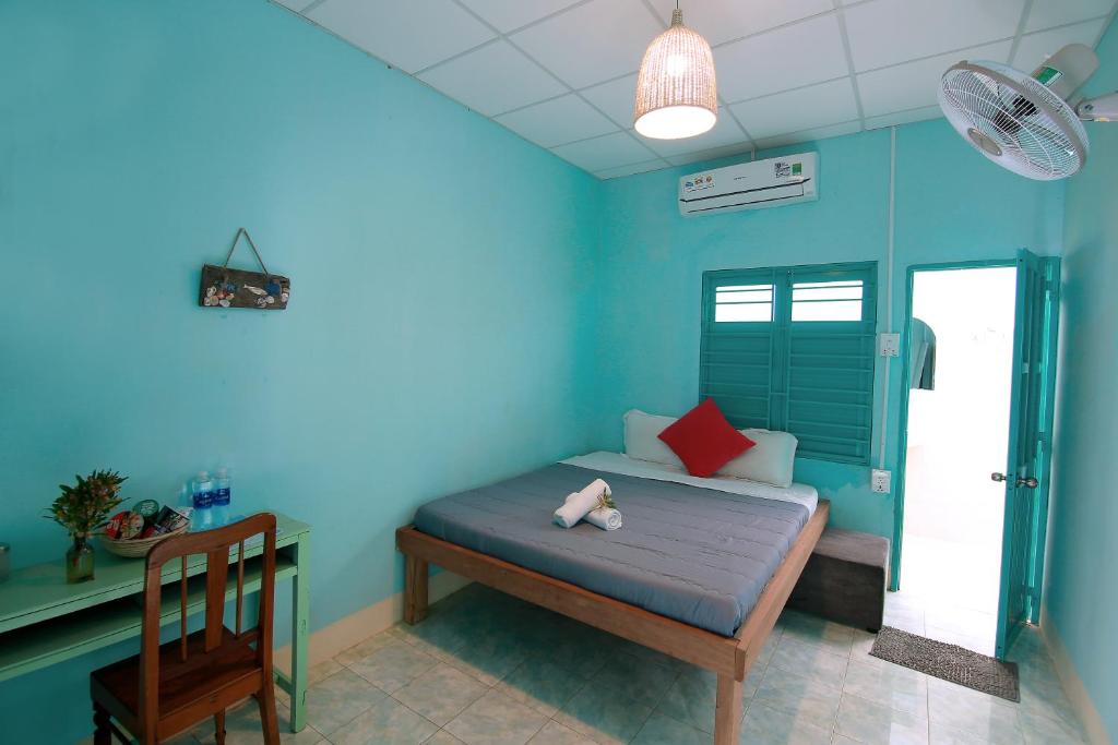 1 dormitorio azul con 1 cama y 1 silla en Yêu Biển homestay, en Phan Rang