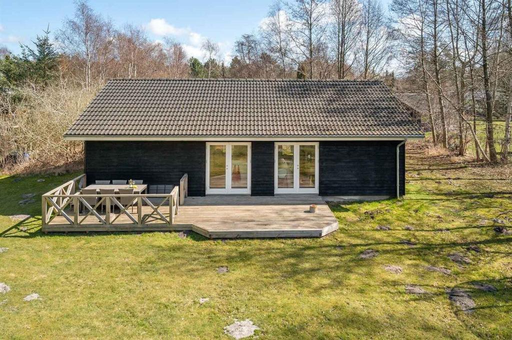 uma pequena casa preta com um deque na relva em Relaxing Vacation In Scenic Surroundings em Højby