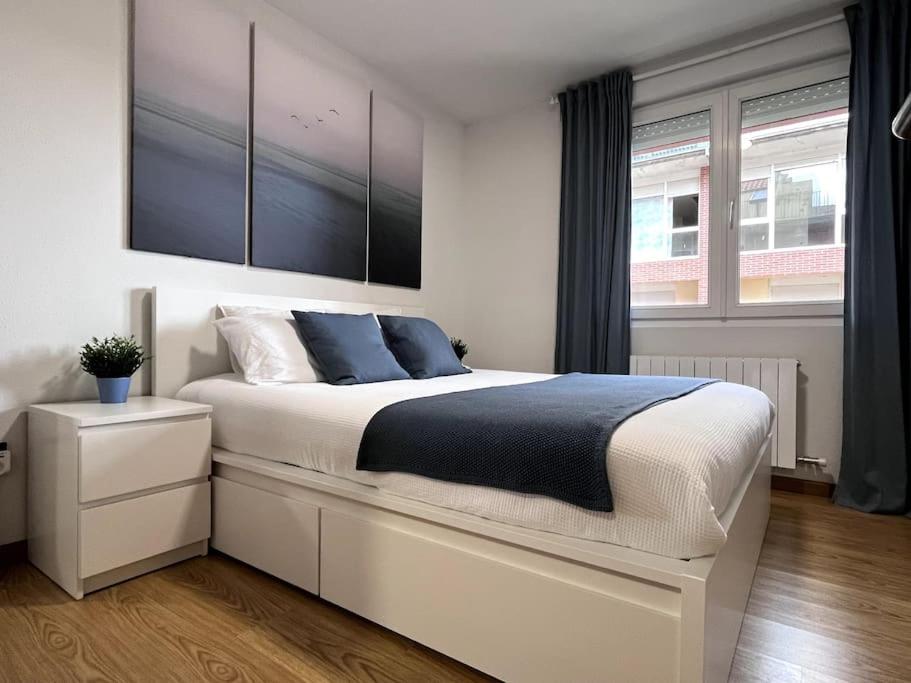 1 dormitorio con 1 cama blanca grande con almohadas azules en Duplex con terraza en Renedo de Piélagos