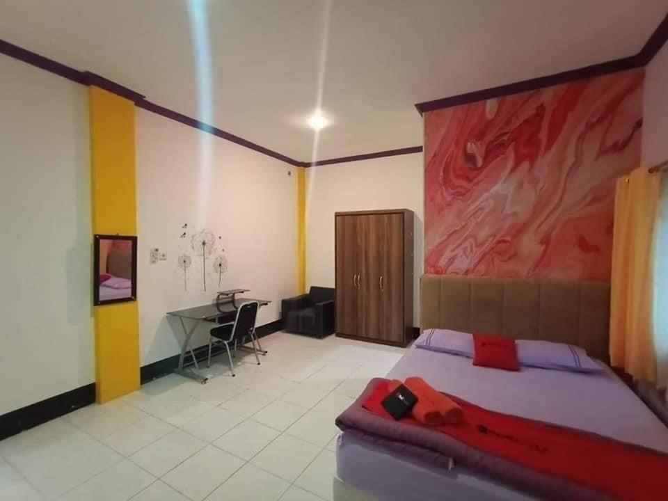 a bedroom with a bed with a painting on the wall at Pavillion EMWEKA Balikpapan in Balikpapan