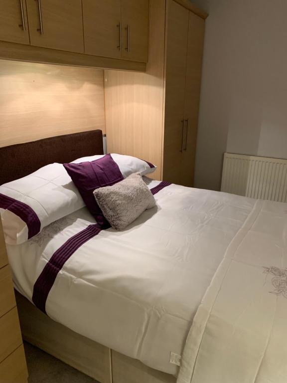 a large bed with purple and white sheets and pillows at Spar Court One bed apartment in Burton upon Trent