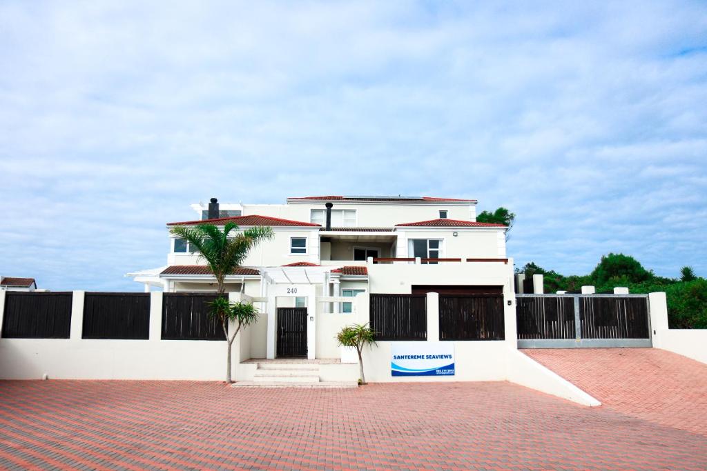 a white house with a fence and a brick driveway at Santareme Seaviews in St Francis Bay