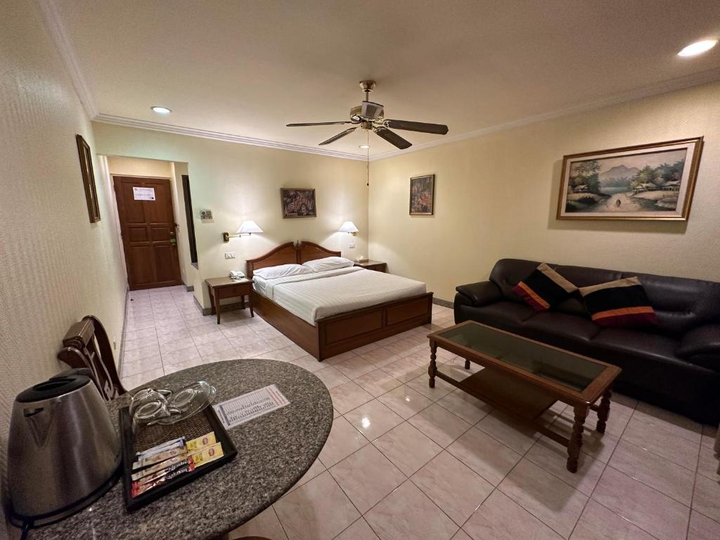 uma sala de estar com uma cama e um sofá em Copa Hotel em Pattaya Central
